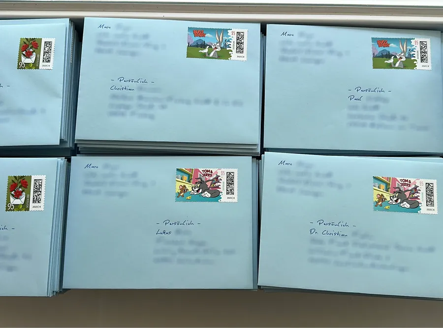 Gestapelte babyblaue Umschläge mit handgeschriebener Adresse und echten Sondermarken